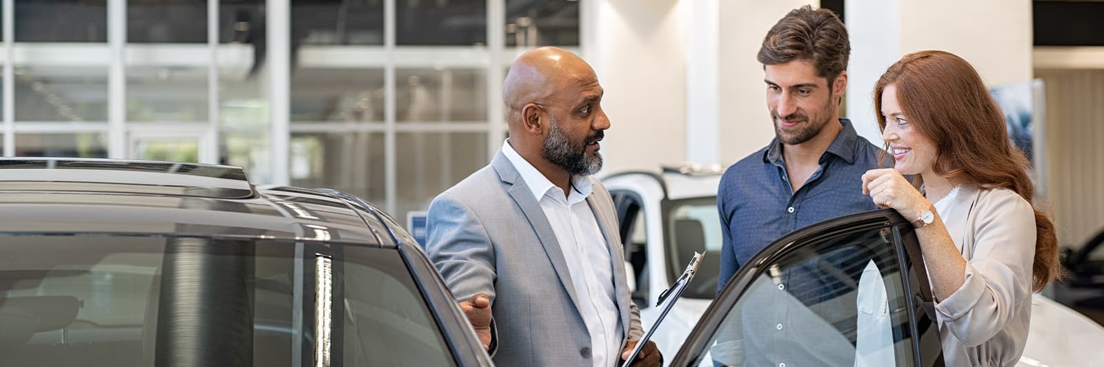 Dealership employee showing customers cars on showroom floor.